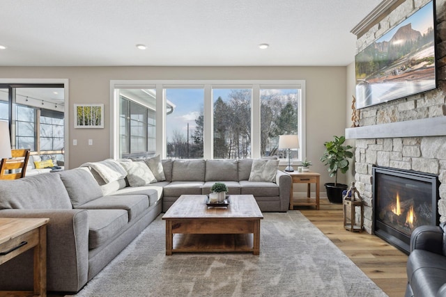 living room featuring light wood-type flooring and a stone fireplace