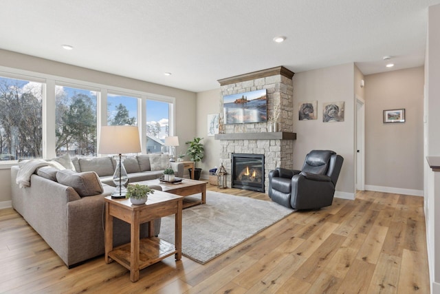 living room with a stone fireplace and light hardwood / wood-style floors