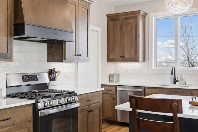 kitchen with sink, tasteful backsplash, appliances with stainless steel finishes, and custom range hood