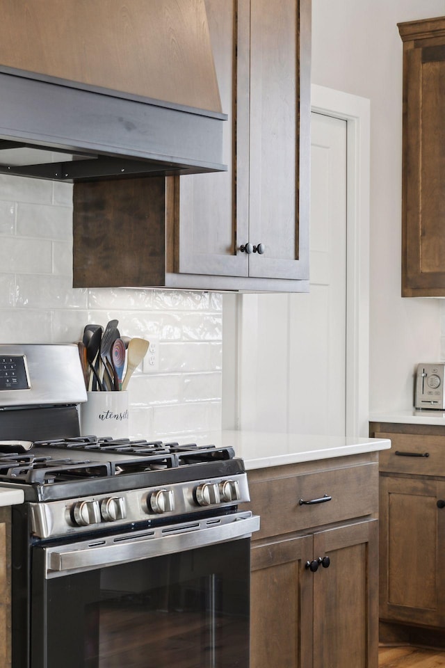 kitchen with decorative backsplash, gas range, and custom range hood