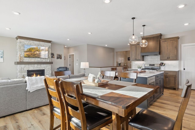 dining area with light wood-type flooring and a stone fireplace