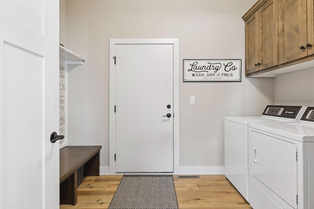 washroom featuring cabinets, washing machine and dryer, and light wood-type flooring