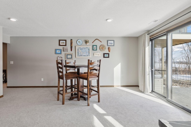 carpeted dining space featuring a textured ceiling