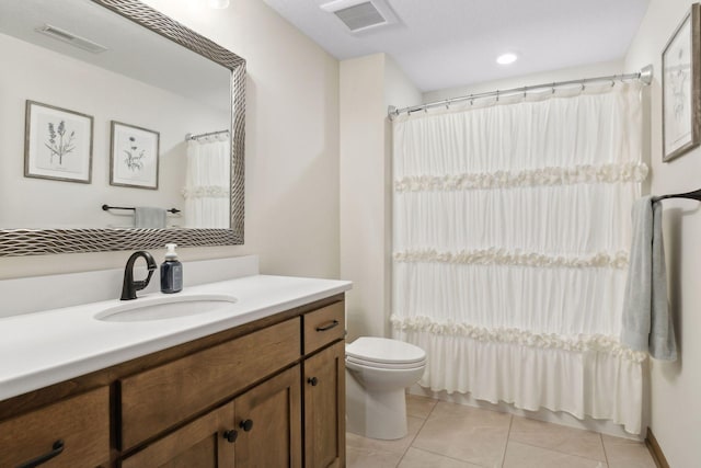 bathroom with toilet, vanity, and tile patterned flooring