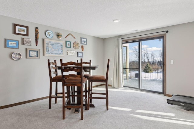 dining area with light colored carpet and a textured ceiling