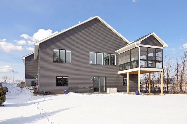 snow covered back of property with a sunroom