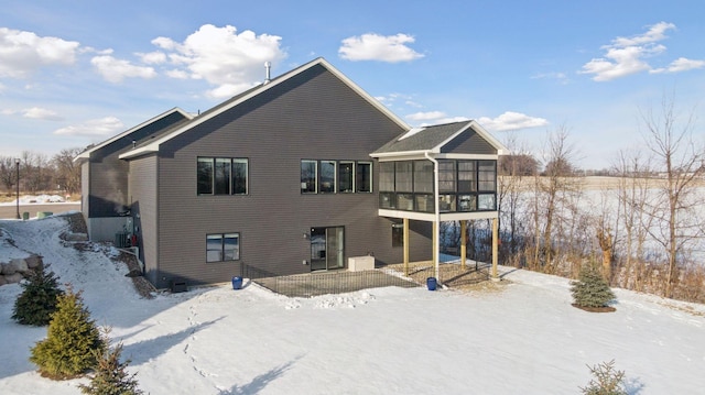 snow covered house featuring a sunroom