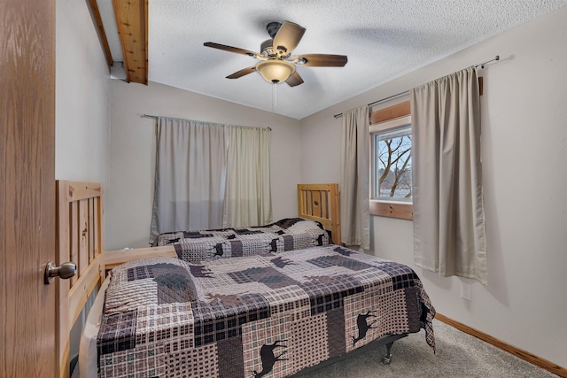 carpeted bedroom with ceiling fan, beamed ceiling, and a textured ceiling