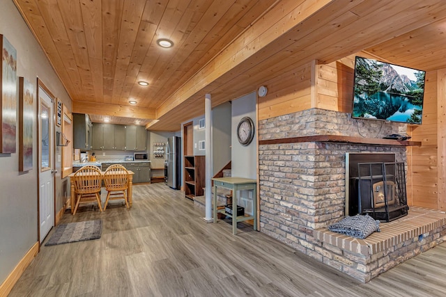 kitchen featuring stainless steel refrigerator, wooden ceiling, wooden walls, and a wood stove