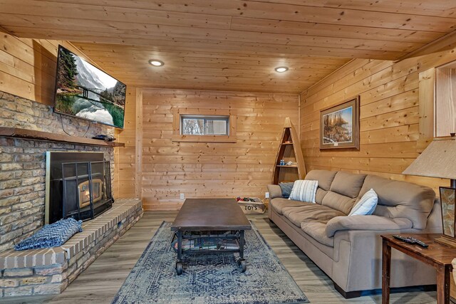 living room featuring light hardwood / wood-style floors, wood ceiling, wooden walls, and a wood stove