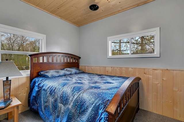 bedroom with wood walls, multiple windows, and carpet