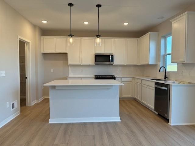 kitchen with decorative light fixtures, a kitchen island, white cabinetry, black dishwasher, and sink