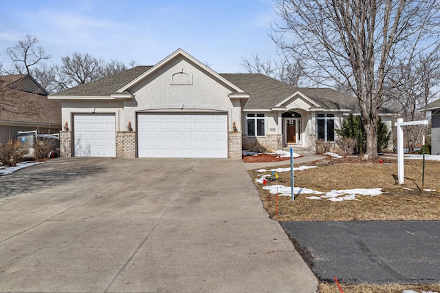 view of front of property with stucco siding, driveway, a shingled roof, a garage, and brick siding