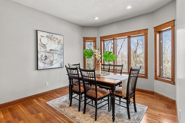 dining room with light wood-type flooring, visible vents, a textured ceiling, recessed lighting, and baseboards