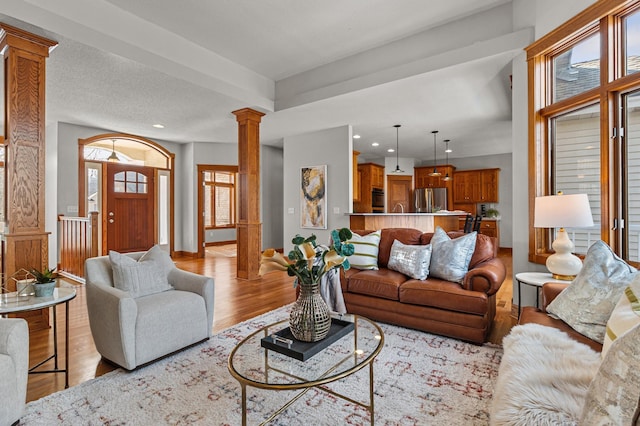 living room featuring recessed lighting, wood finished floors, baseboards, and decorative columns