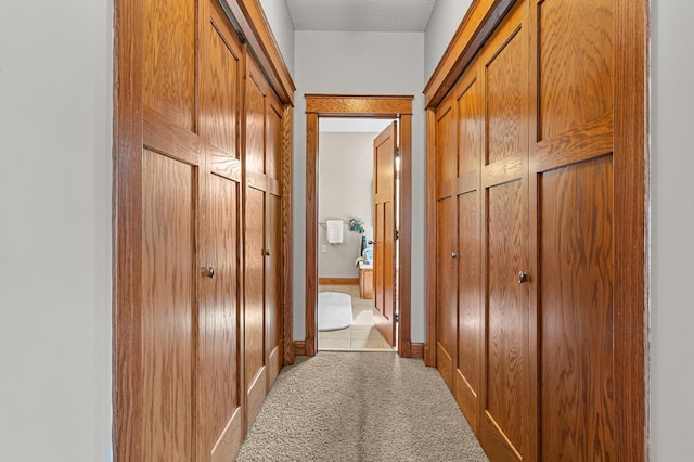 hall with a barn door, baseboards, and carpet flooring