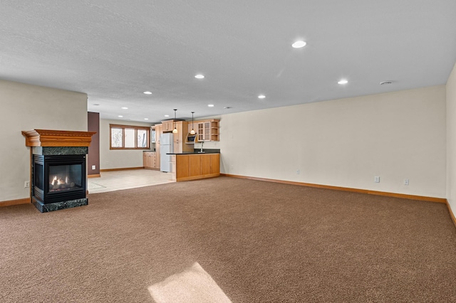 unfurnished living room featuring light carpet, recessed lighting, baseboards, and a premium fireplace