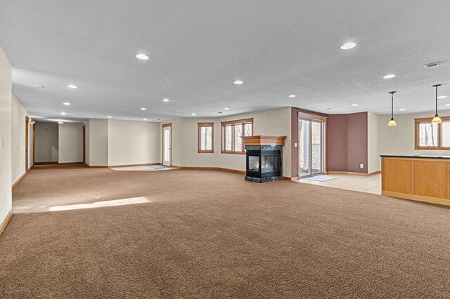 unfurnished living room with baseboards, a multi sided fireplace, light carpet, recessed lighting, and a textured ceiling