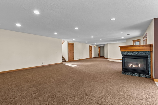 unfurnished living room with recessed lighting, stairway, carpet flooring, a premium fireplace, and baseboards