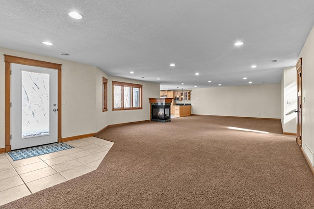 unfurnished living room featuring recessed lighting, light colored carpet, a multi sided fireplace, and a textured ceiling