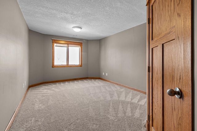 carpeted empty room with baseboards and a textured ceiling