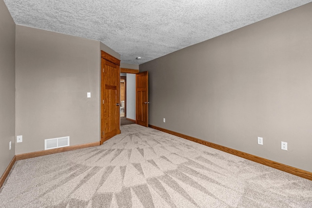 empty room with visible vents, baseboards, a textured ceiling, and carpet