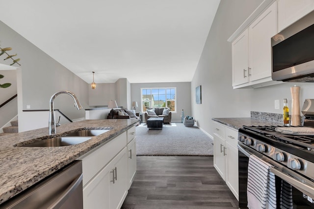 kitchen with stainless steel appliances, light stone countertops, white cabinets, and sink