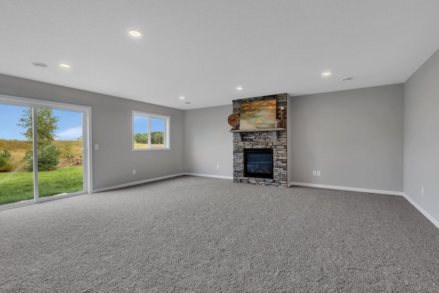 unfurnished living room with carpet floors and a stone fireplace