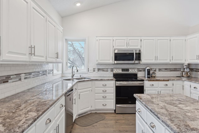 kitchen featuring light stone counters, sink, white cabinets, and stainless steel appliances