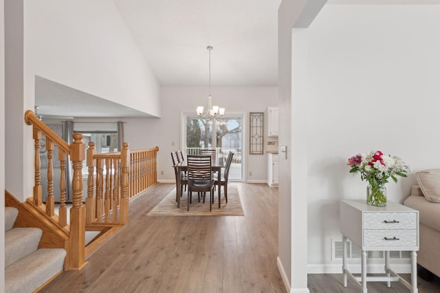 dining area with a notable chandelier, high vaulted ceiling, and wood-type flooring