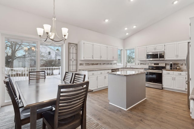 kitchen featuring a kitchen island, white cabinets, hanging light fixtures, and stainless steel appliances