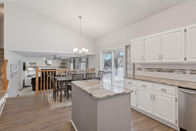 kitchen featuring pendant lighting, vaulted ceiling, dishwasher, white cabinets, and a center island