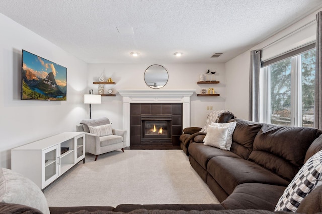 carpeted living room with a tile fireplace and a textured ceiling