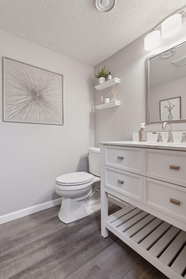 bathroom featuring vanity, toilet, hardwood / wood-style floors, and a textured ceiling