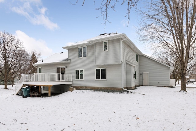 snow covered house featuring a wooden deck