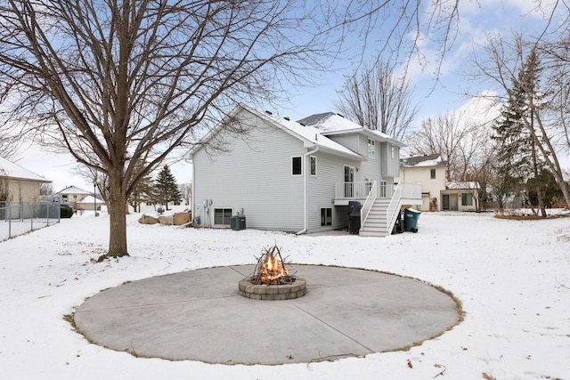 snow covered house featuring a wooden deck, an outdoor fire pit, and central AC unit