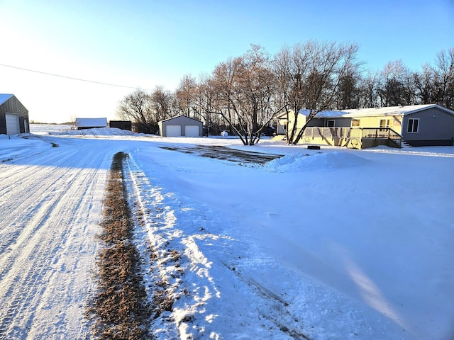 snowy yard with a garage and an outbuilding