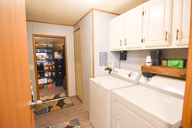 laundry area with light hardwood / wood-style floors, cabinets, a textured ceiling, and washing machine and clothes dryer