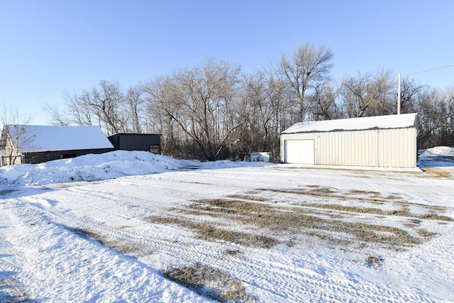 yard layered in snow with a garage and an outbuilding