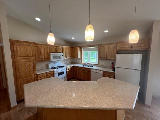 kitchen with white appliances, hanging light fixtures, a kitchen island, and sink