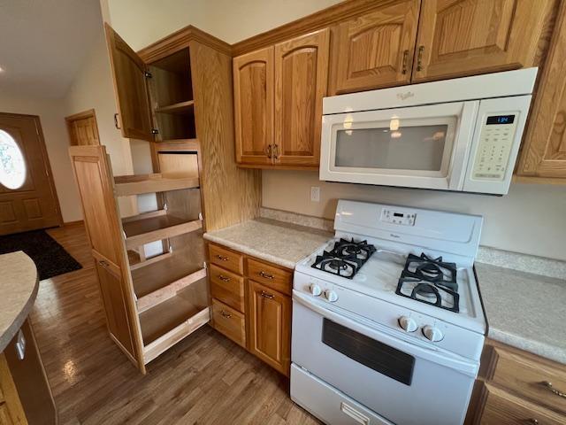 kitchen with lofted ceiling, white appliances, and hardwood / wood-style flooring