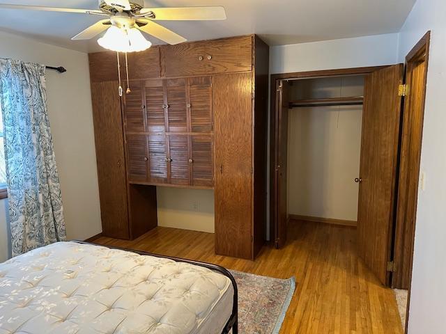 bedroom featuring a closet, built in desk, ceiling fan, and light hardwood / wood-style floors