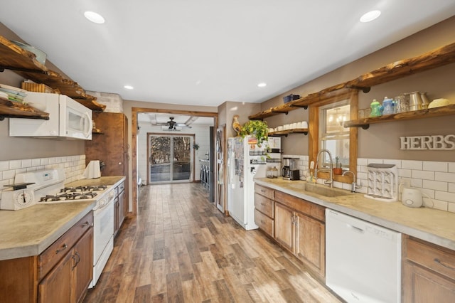 kitchen with sink, backsplash, white appliances, and light hardwood / wood-style flooring