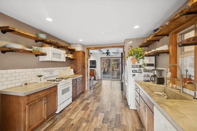 kitchen with sink, white appliances, light hardwood / wood-style flooring, ceiling fan, and tasteful backsplash