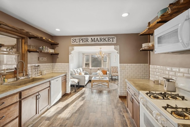 kitchen featuring pendant lighting, sink, a notable chandelier, white appliances, and light hardwood / wood-style flooring