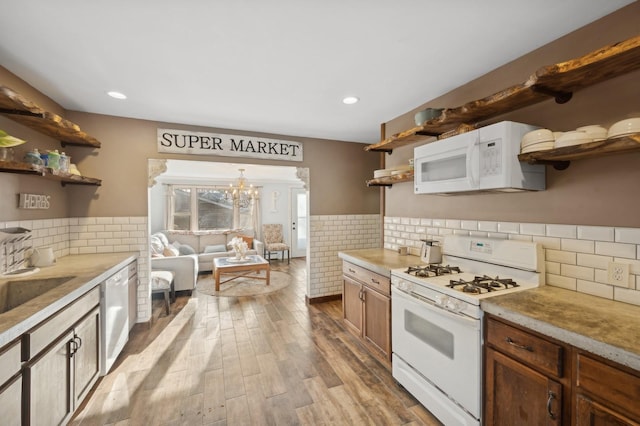 kitchen with decorative light fixtures, tasteful backsplash, sink, white appliances, and light wood-type flooring