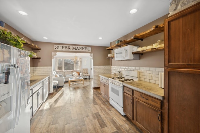 kitchen featuring white appliances, a chandelier, light hardwood / wood-style floors, and decorative backsplash