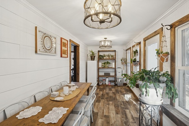 dining space with an inviting chandelier, crown molding, and dark hardwood / wood-style floors