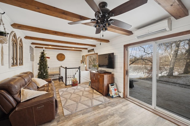 living room with ceiling fan, an AC wall unit, beamed ceiling, and light wood-type flooring