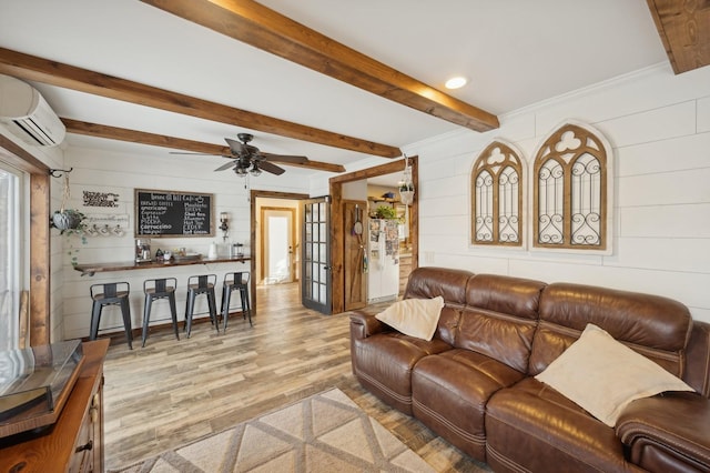 living room with beam ceiling, an AC wall unit, light hardwood / wood-style floors, and french doors